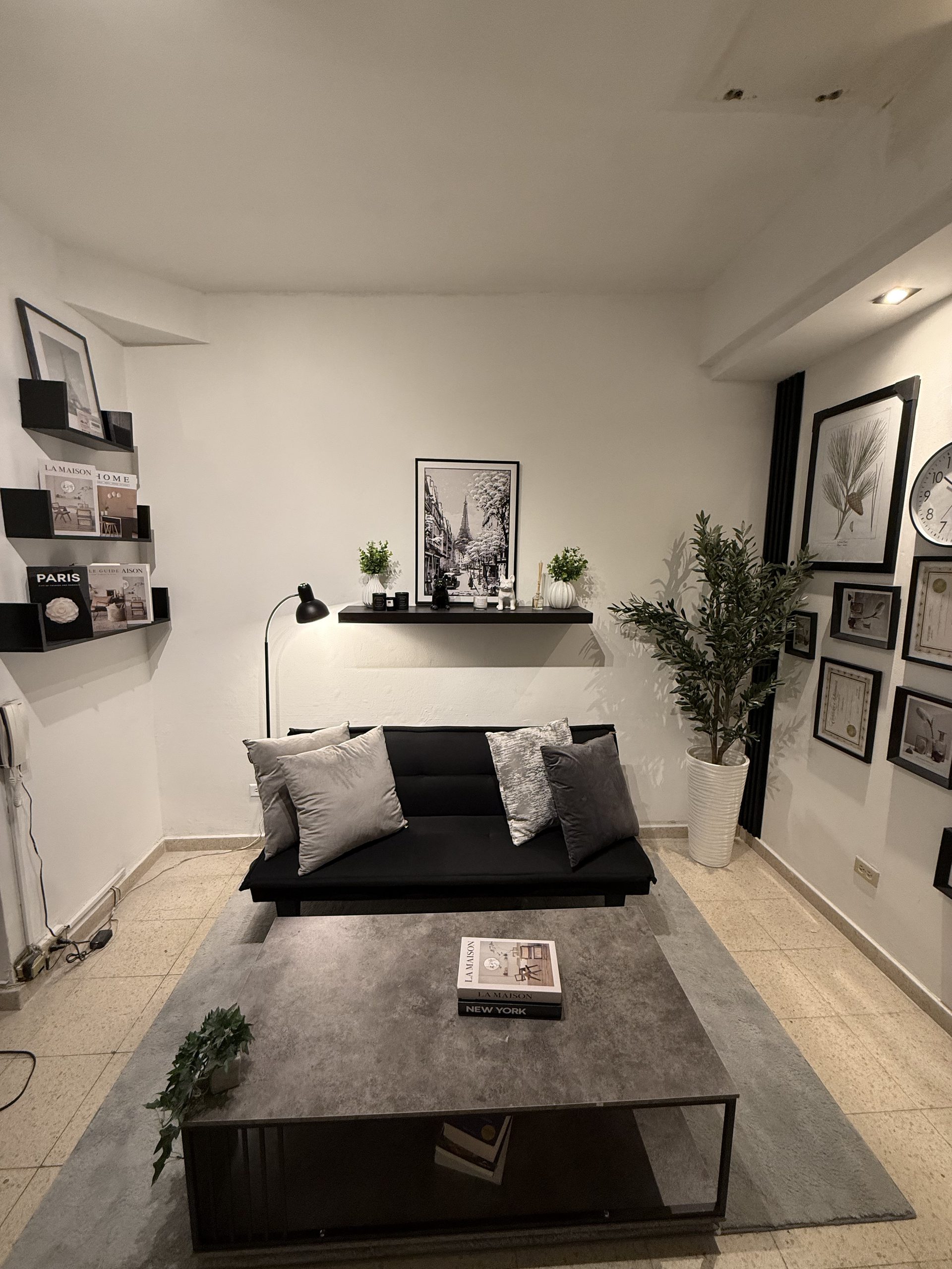 Sala de espera con sofá negro, gallery wall y mesa de centro