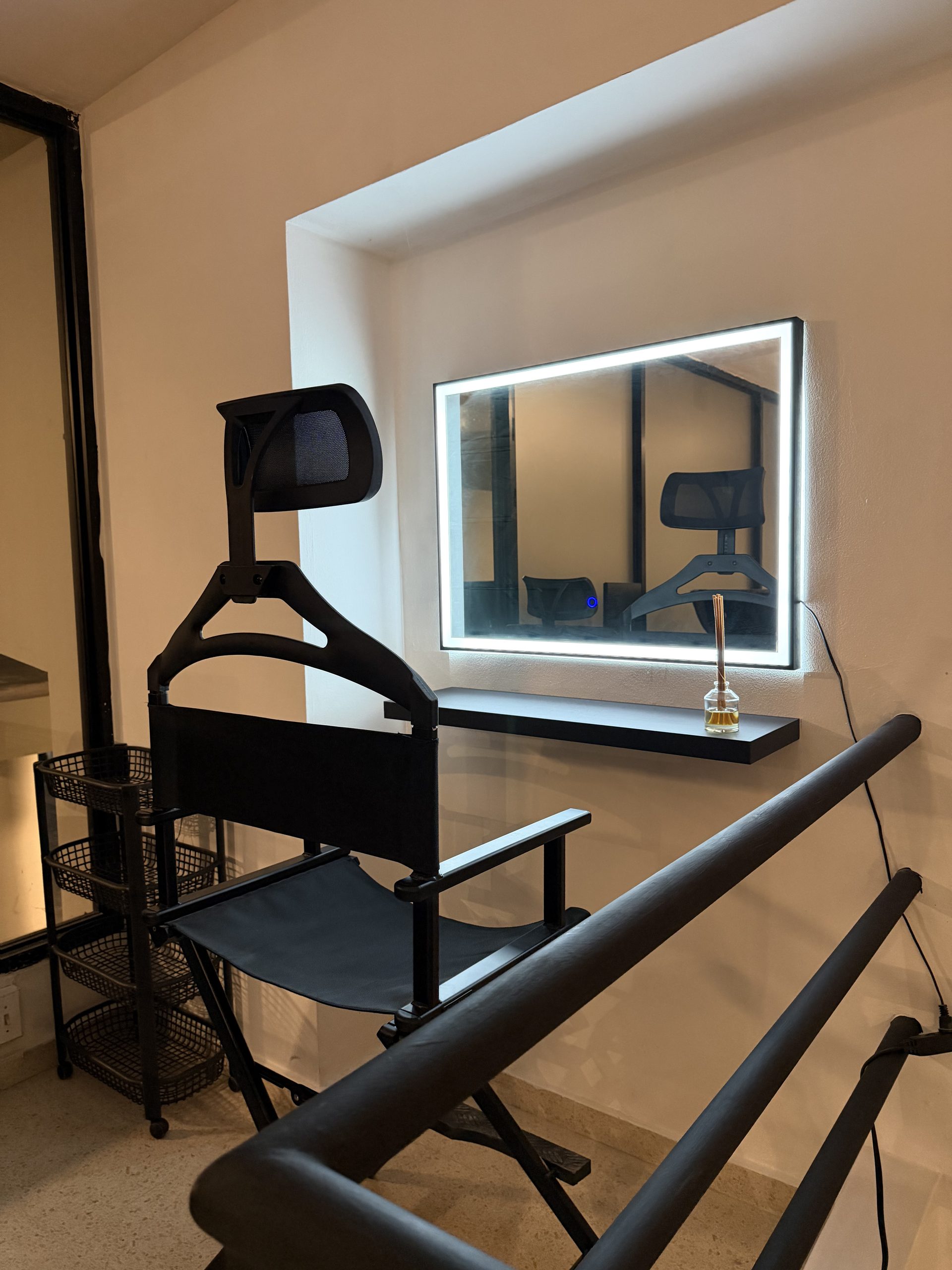 Área de maquillaje y peinado con espejo LED y silla de director